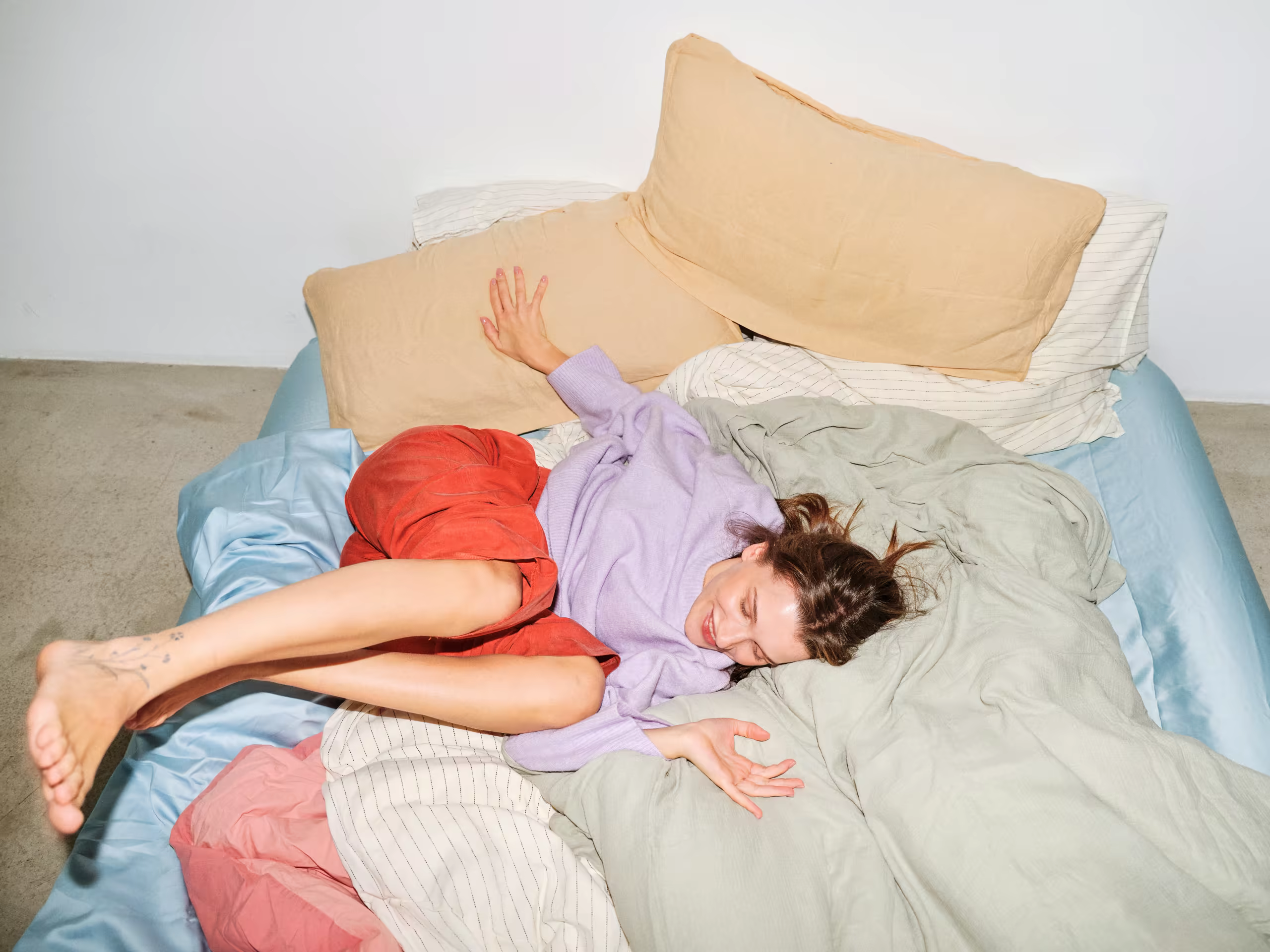 A woman relaxing among colorful, softly rumpled bedding
